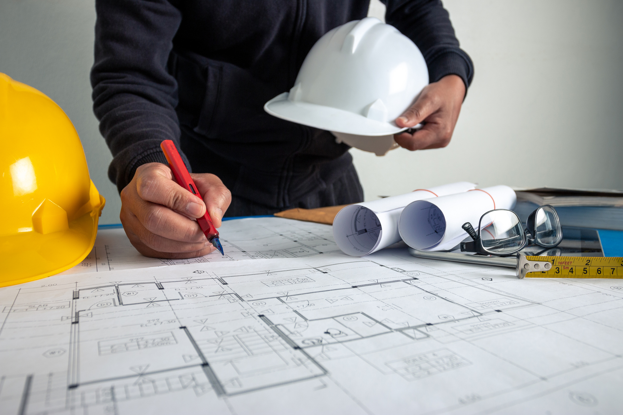 The architect is working to design the building at the office desk.
